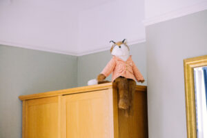 A stuffed animal teddy bear sat on top of a wardrobe